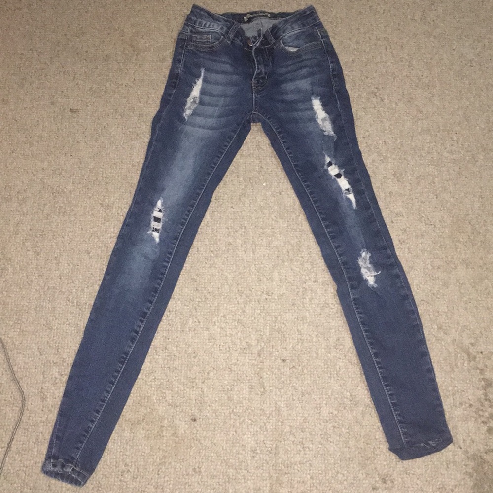 Slightly ripped, dark blue jeans .